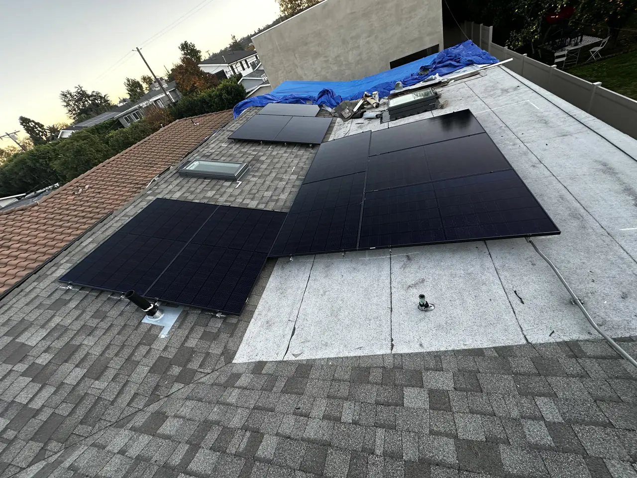 Black solar modules being laid across a composition shingle roof, Sherman Oaks