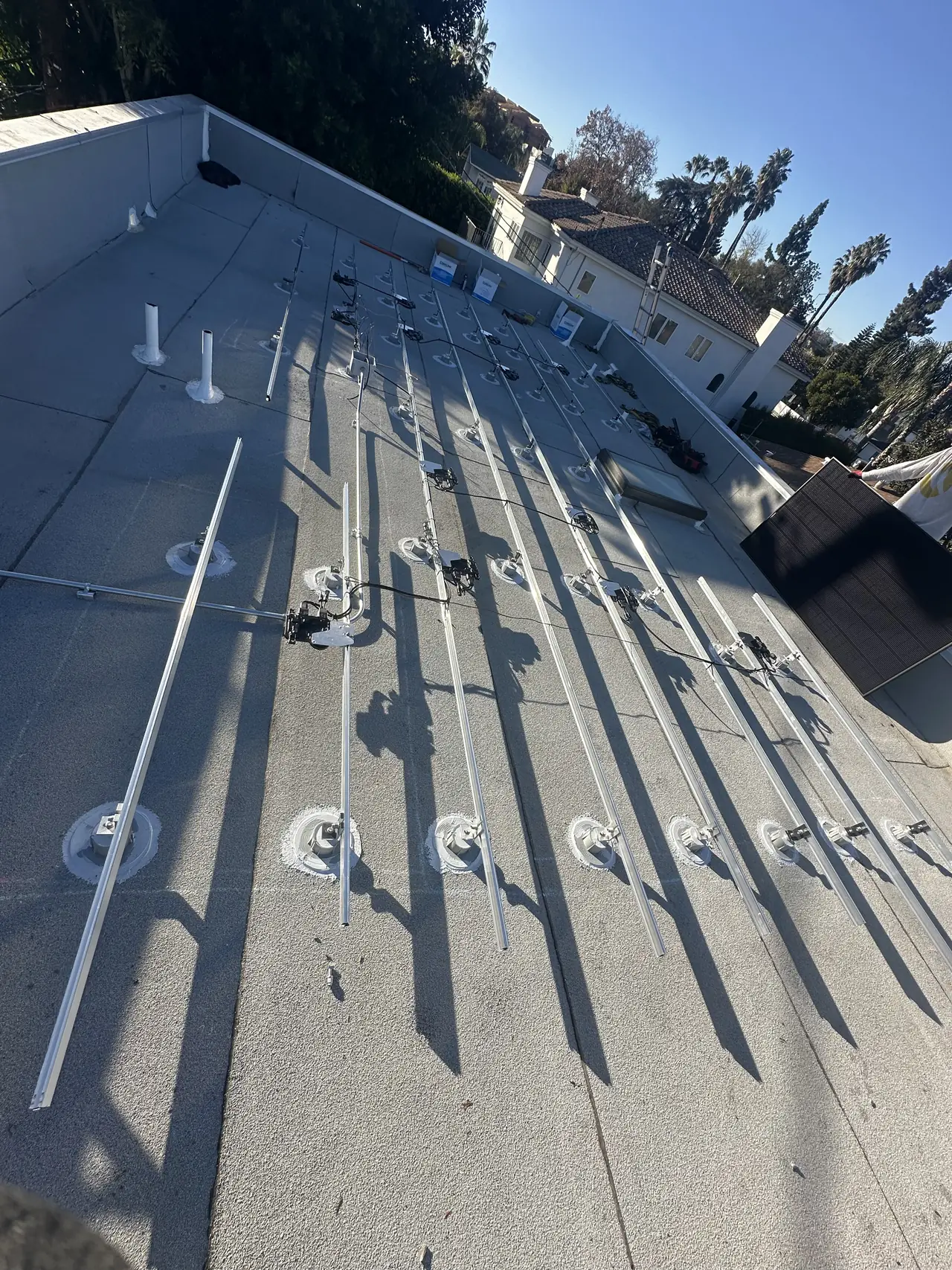 Racking rails laid across a low-slope roof before modules, Sherman Oaks