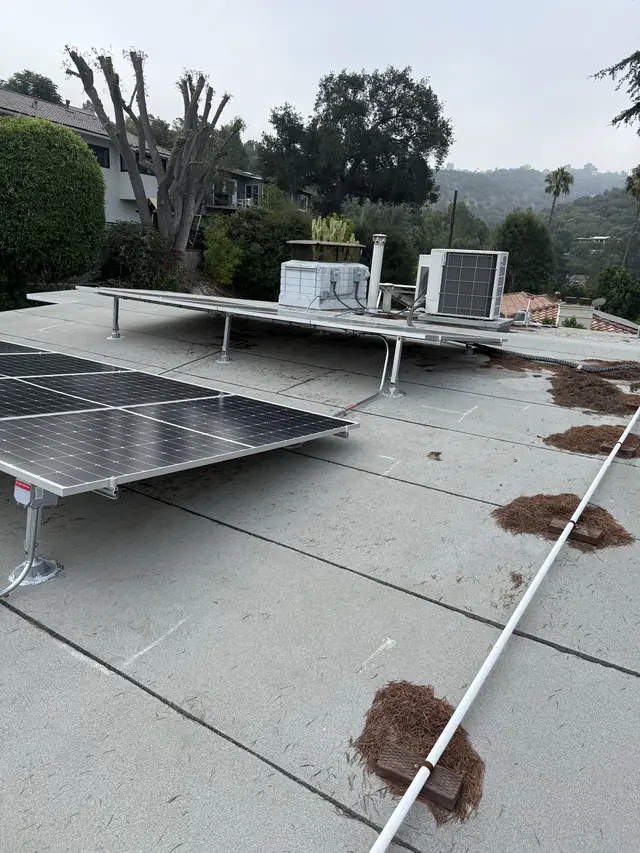 Solar modules on tilt racking across a low-slope roof against a blue sky, Sherman Oaks