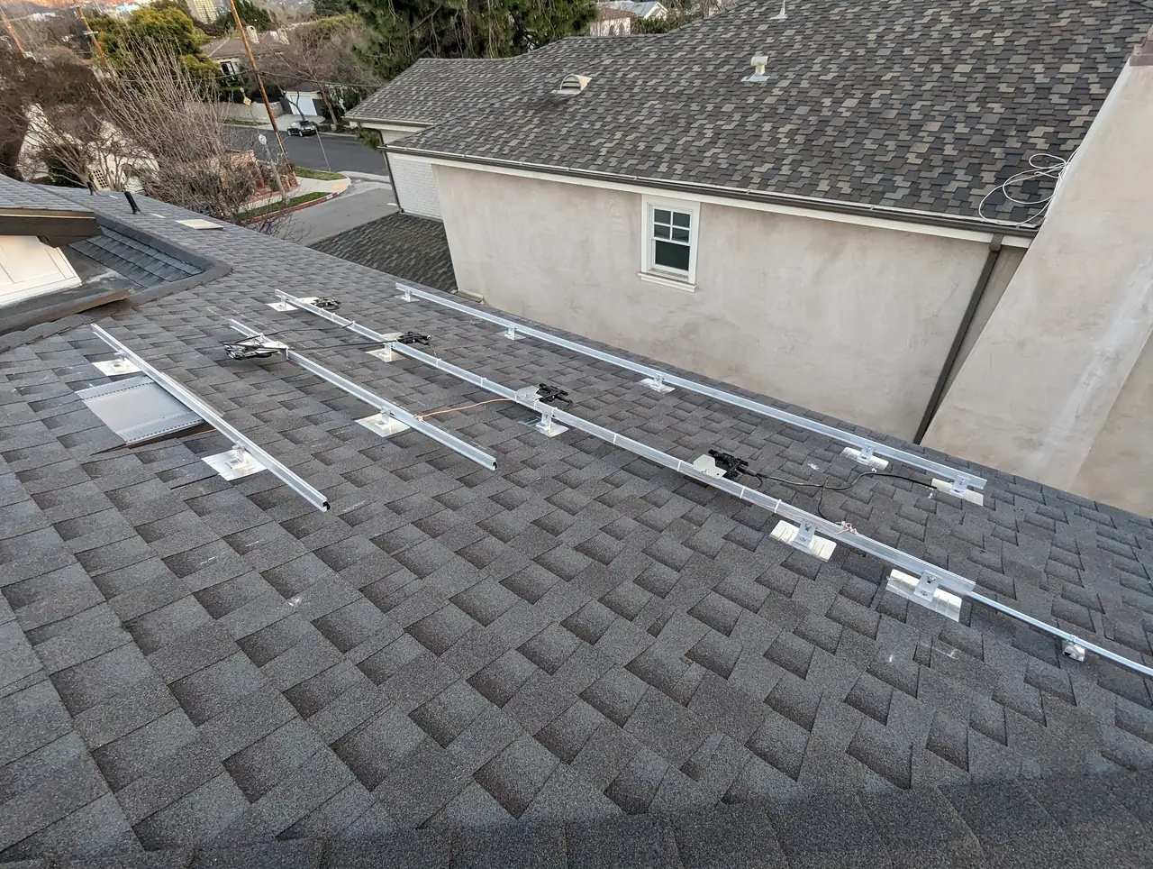 Mounting rails laid out across a new composition shingle roof with a neighboring house beyond, Studio City