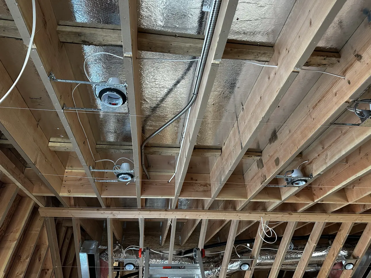 Electrical conduit and cable runs through open ceiling joists in a house under construction, Studio City
