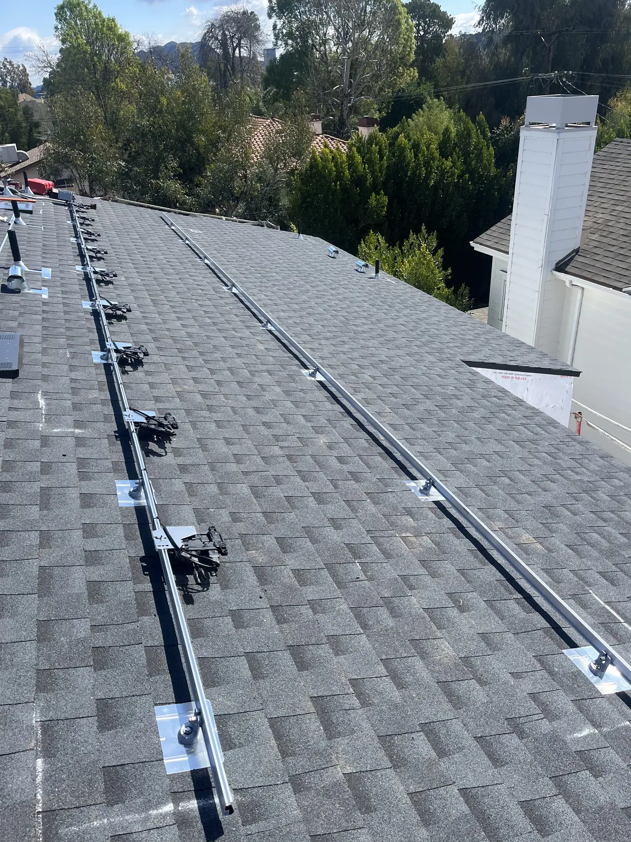 Mounting rails running the length of a shingle roof beside a chimney, Studio City