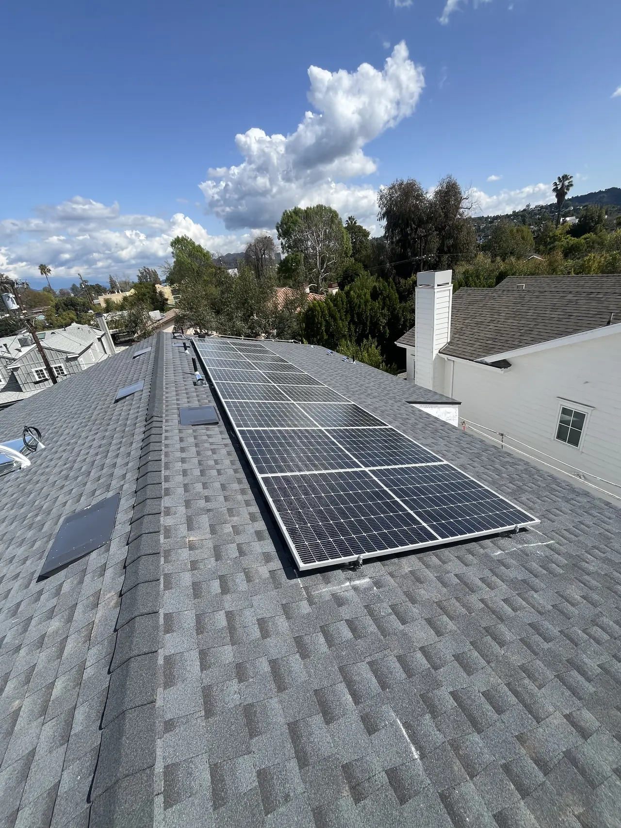 Finished solar array across two planes of a shingle roof with clouds overhead, Studio City