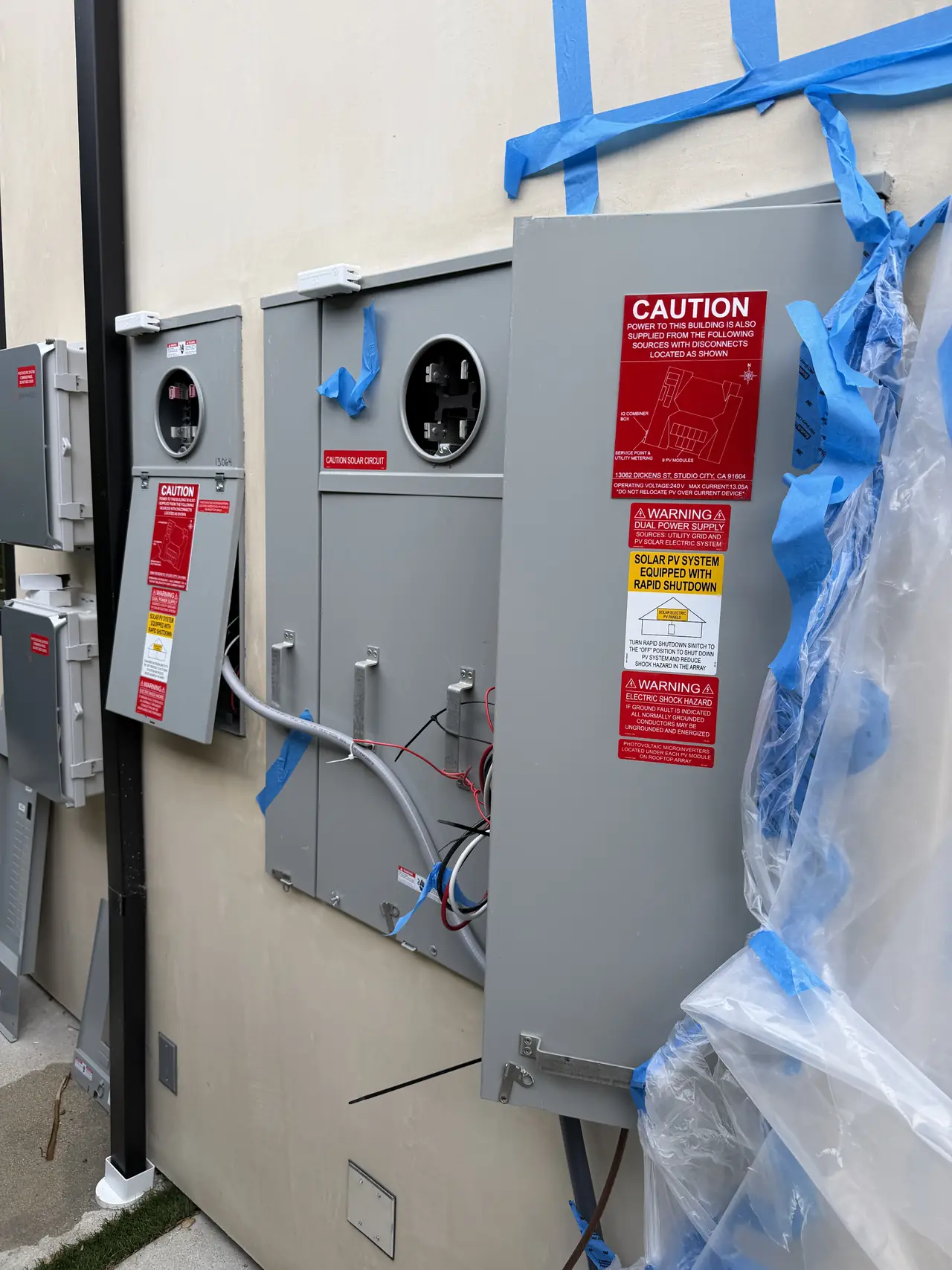 Electrical enclosures mounted on an unfinished exterior wall, still wrapped in protective film and masking tape, Studio City