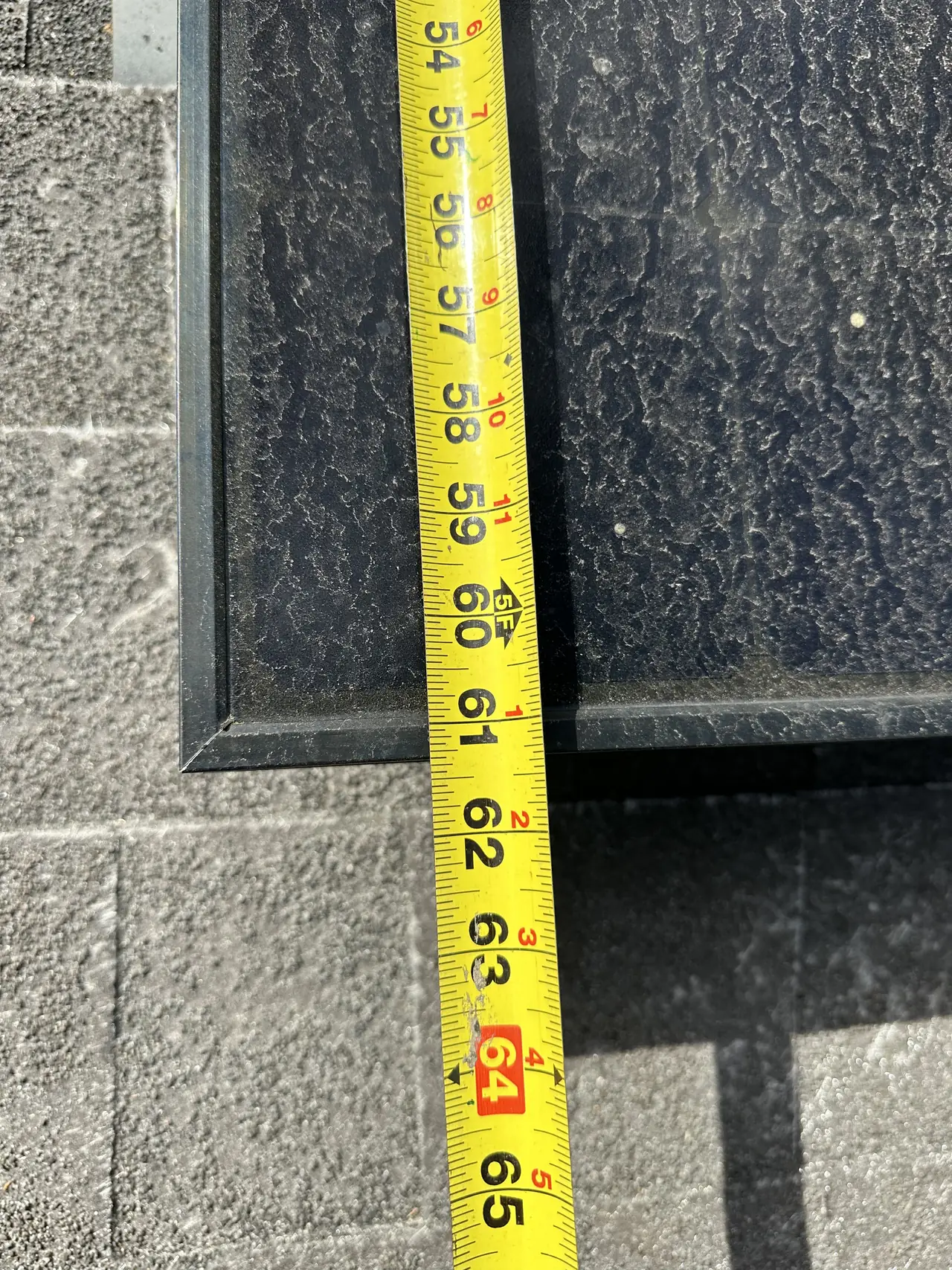 A tape measure held against the edge of a roof section, reading in inches, Studio City