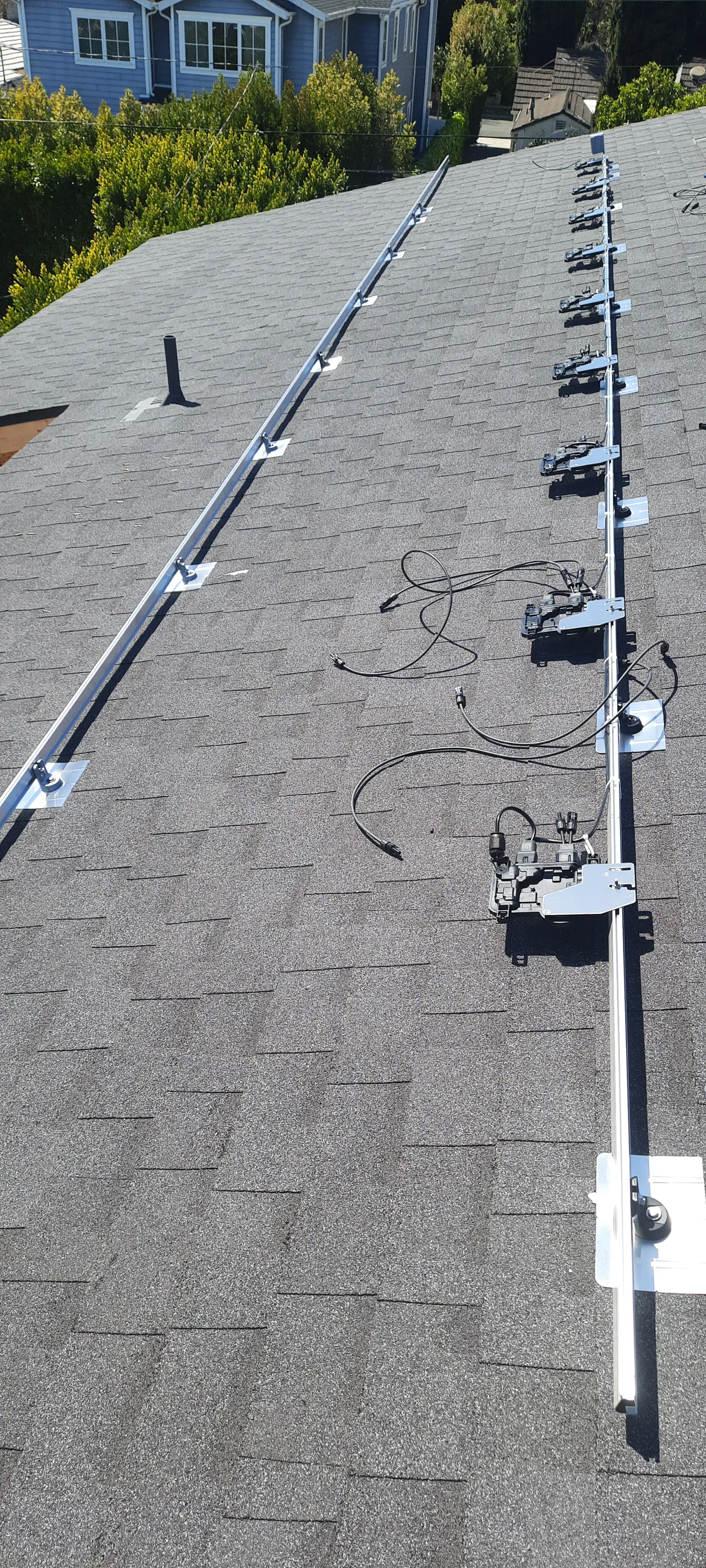 Mounting rails and clamps running up a shingle roof with the module cabling dressed along them, Studio City