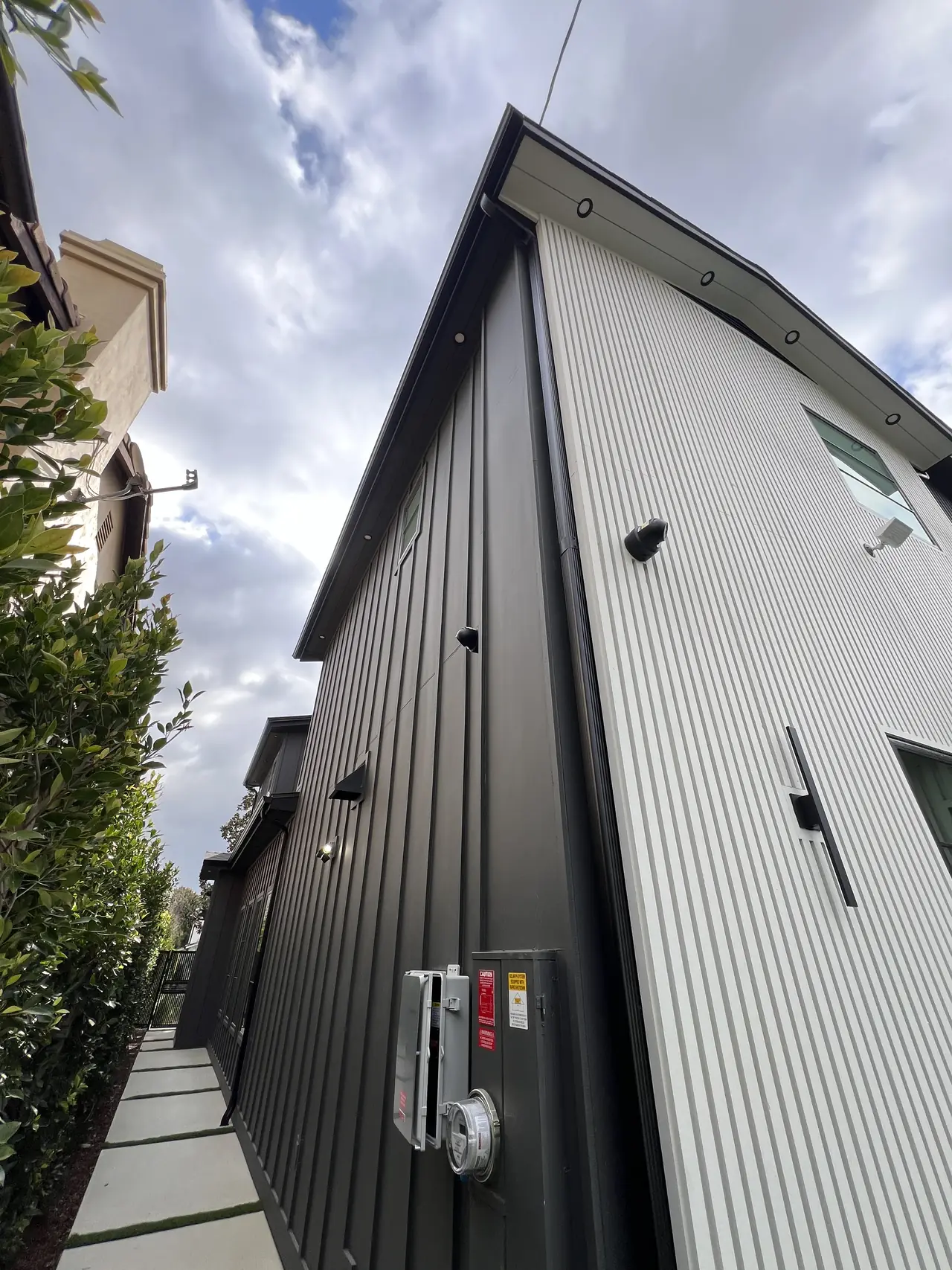 The side wall of a two-story house with the electrical equipment mounted along it, Studio City