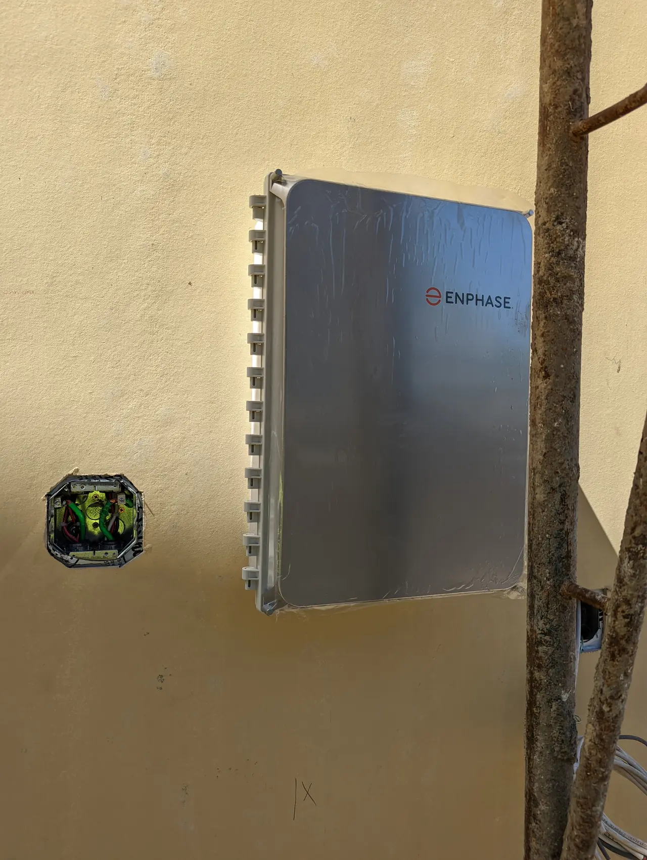An Enphase combiner enclosure mounted on a stucco wall, closed and labeled, Studio City