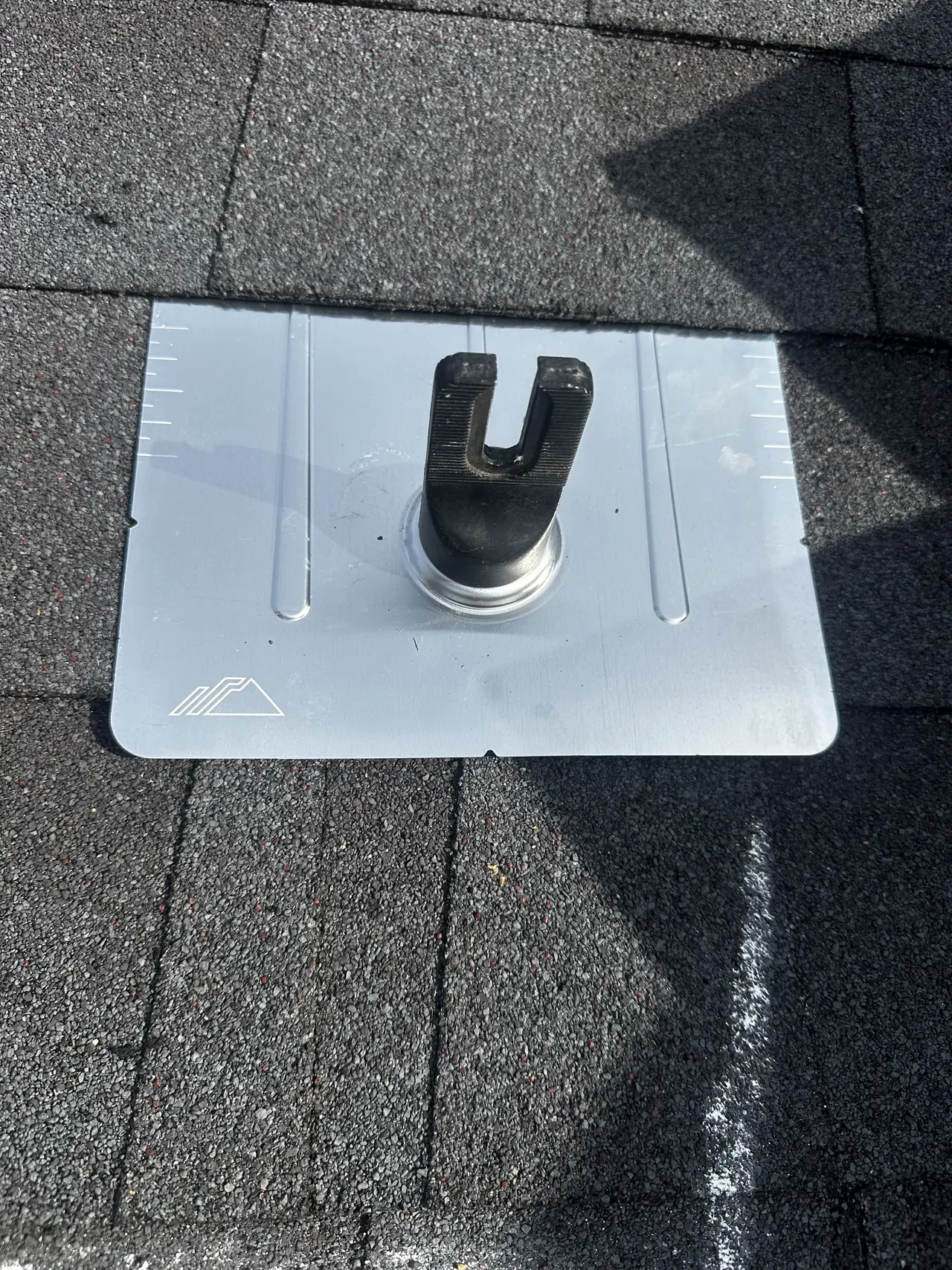 A metal flashing plate set into a shingle roof with a mounting foot standing proud of it, Studio City