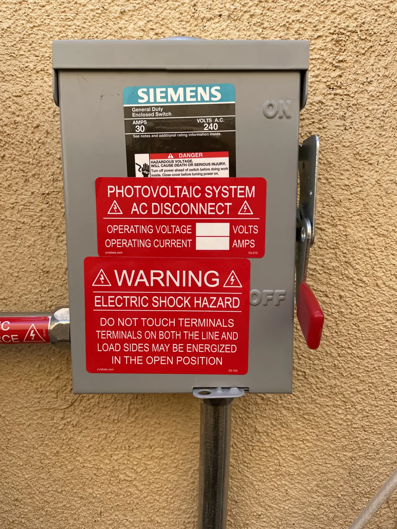 AC disconnect with a photovoltaic system warning label on an exterior wall, Sun Valley