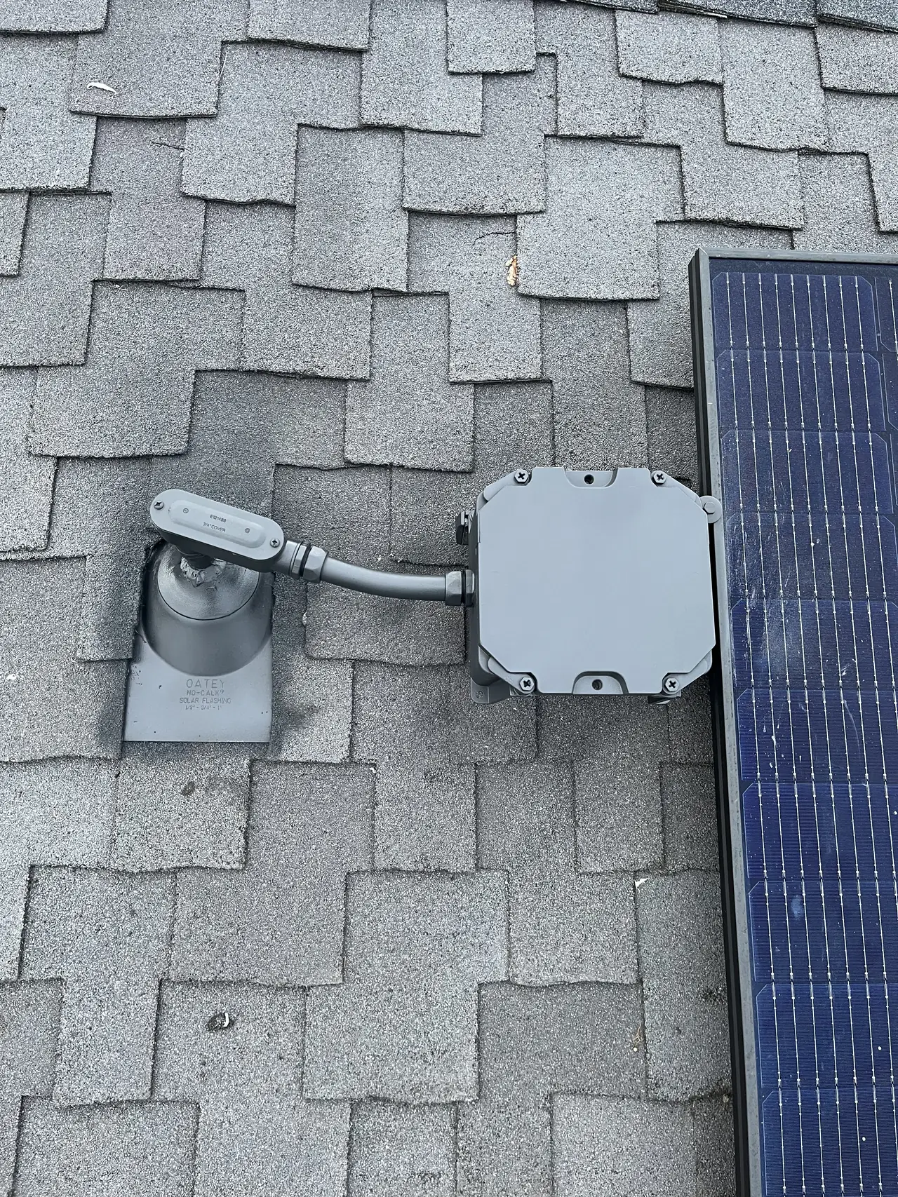 Junction box and conduit on a composition shingle roof beside a solar module, Sun Valley
