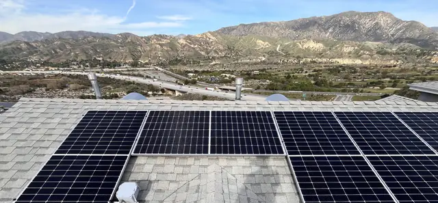 Solar modules in several groups on a gray shingle hip roof with foothills beyond, Sunland