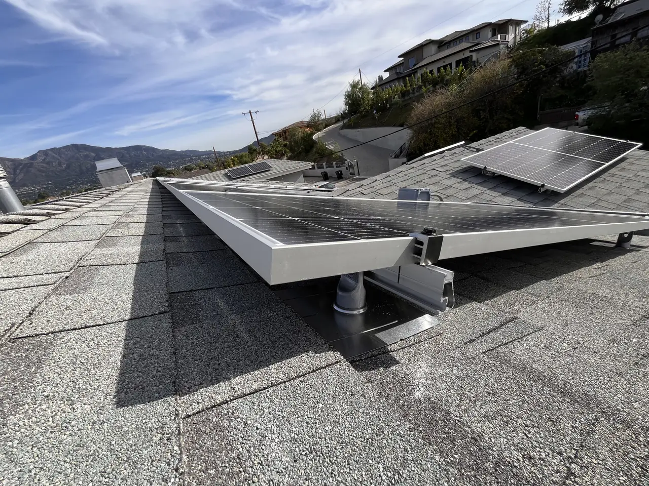 Solar modules on tilt legs over a low-slope section of roof, beside a shingle slope, Sunland