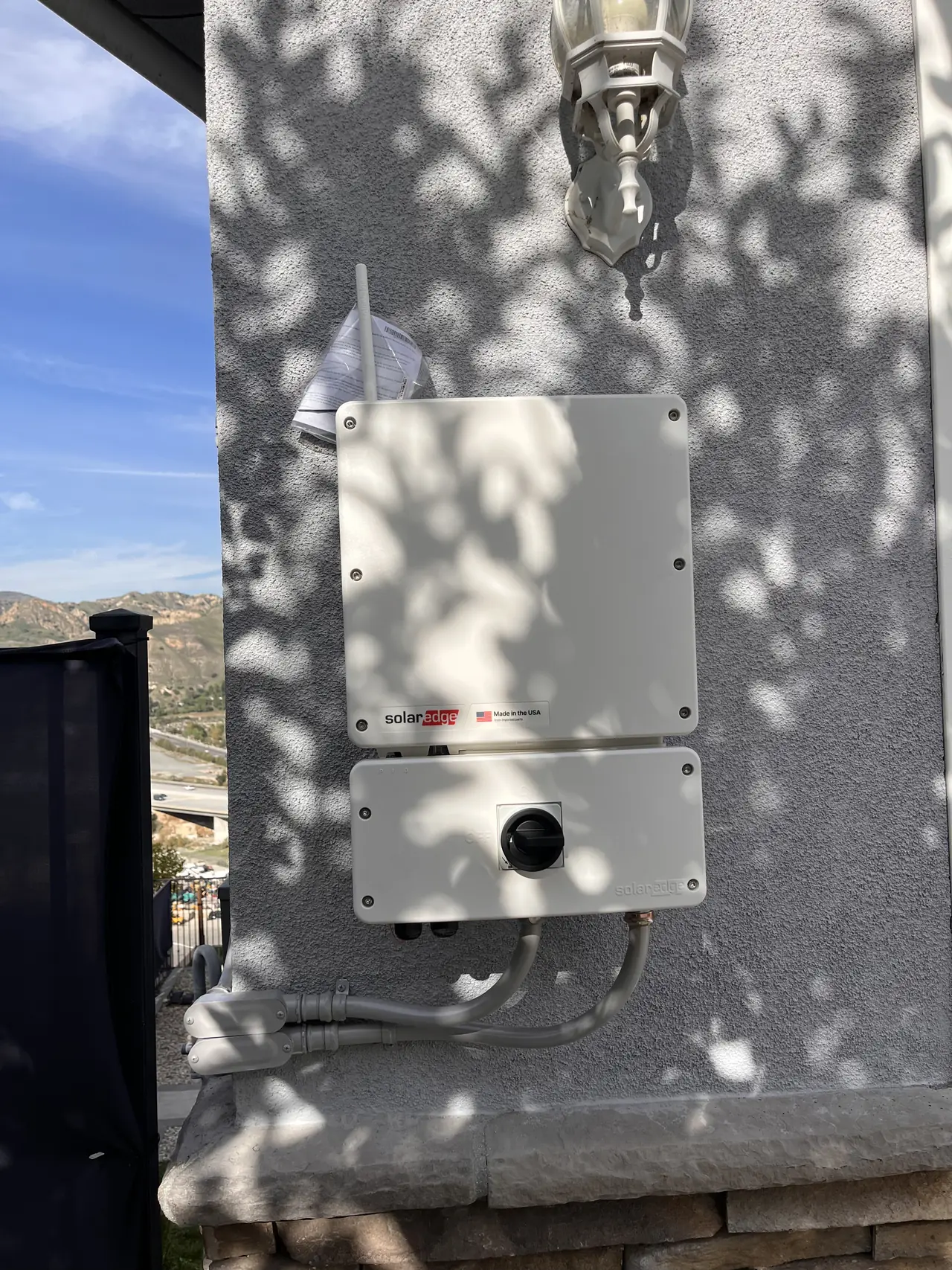 A SolarEdge inverter with its disconnect mounted on a stucco wall, Sunland
