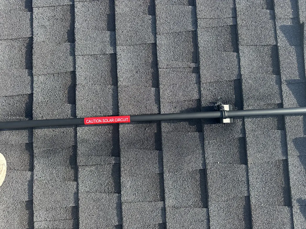 Conduit on a shingle roof with a red CAUTION SOLAR CIRCUIT label, Sunland