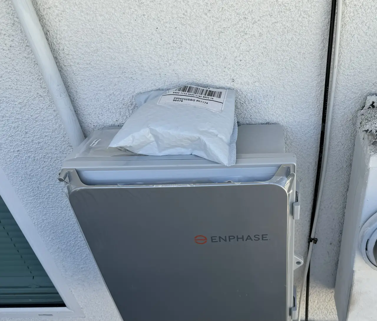 An Enphase combiner box mounted on a stucco wall beside the electrical service, Sunland