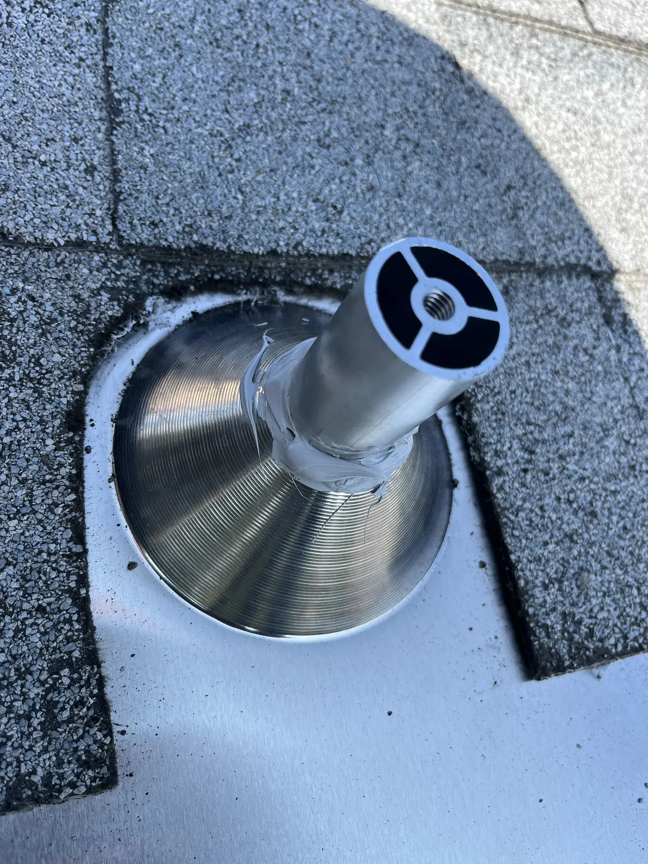 A standoff post rising from a conical metal flashing tucked under the shingles, Sunland