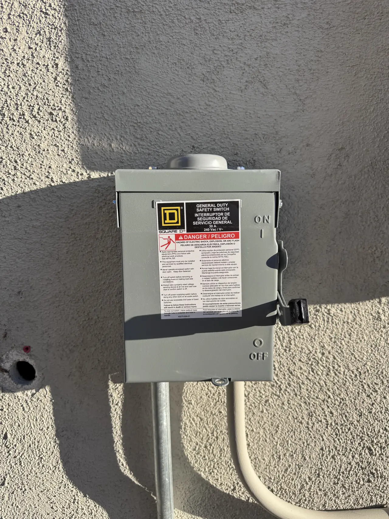 A Square D safety switch mounted on a stucco wall with conduit entering from below, Sunland