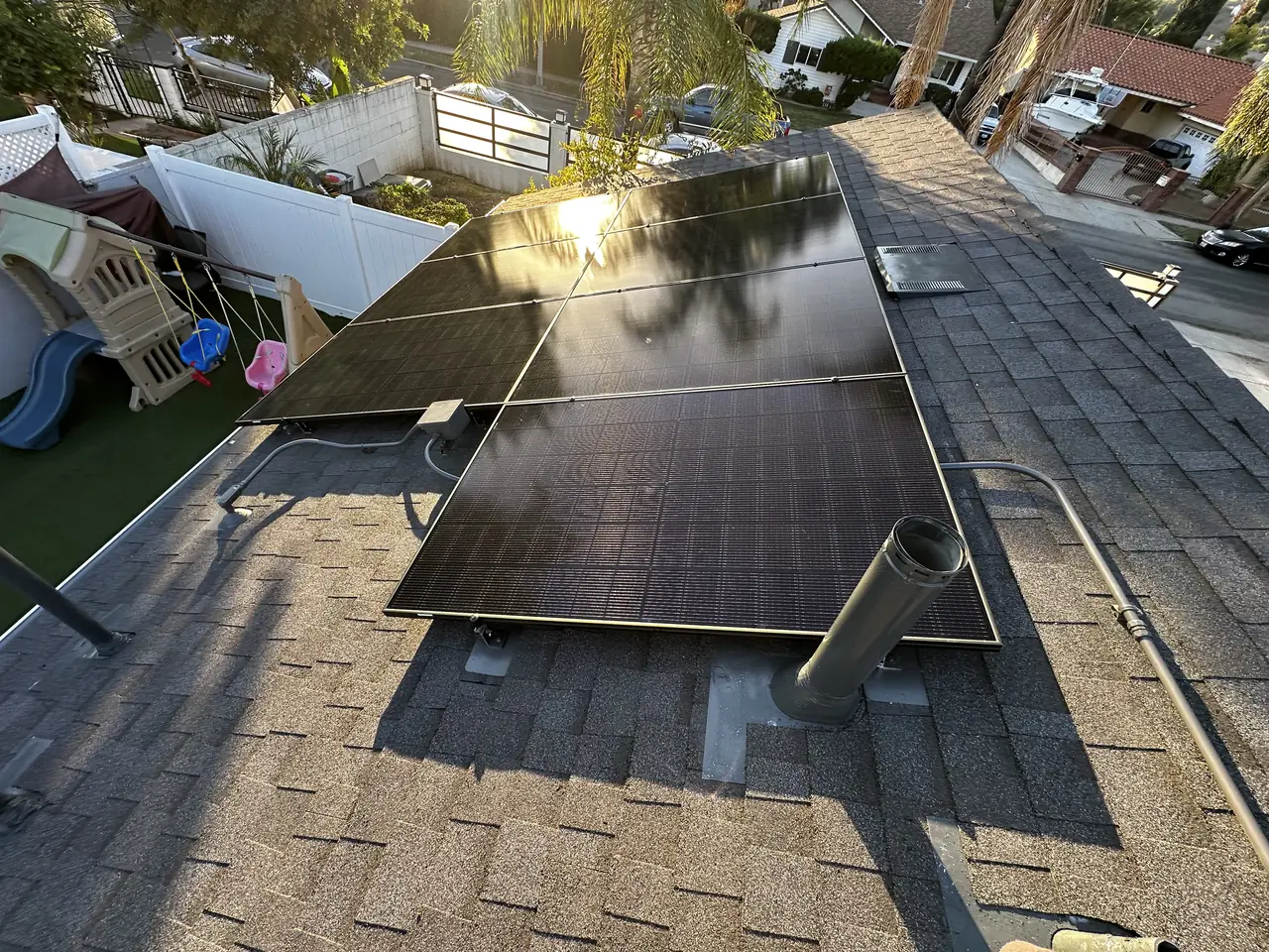Solar modules on two planes of a composition shingle roof above a back yard, Sylmar