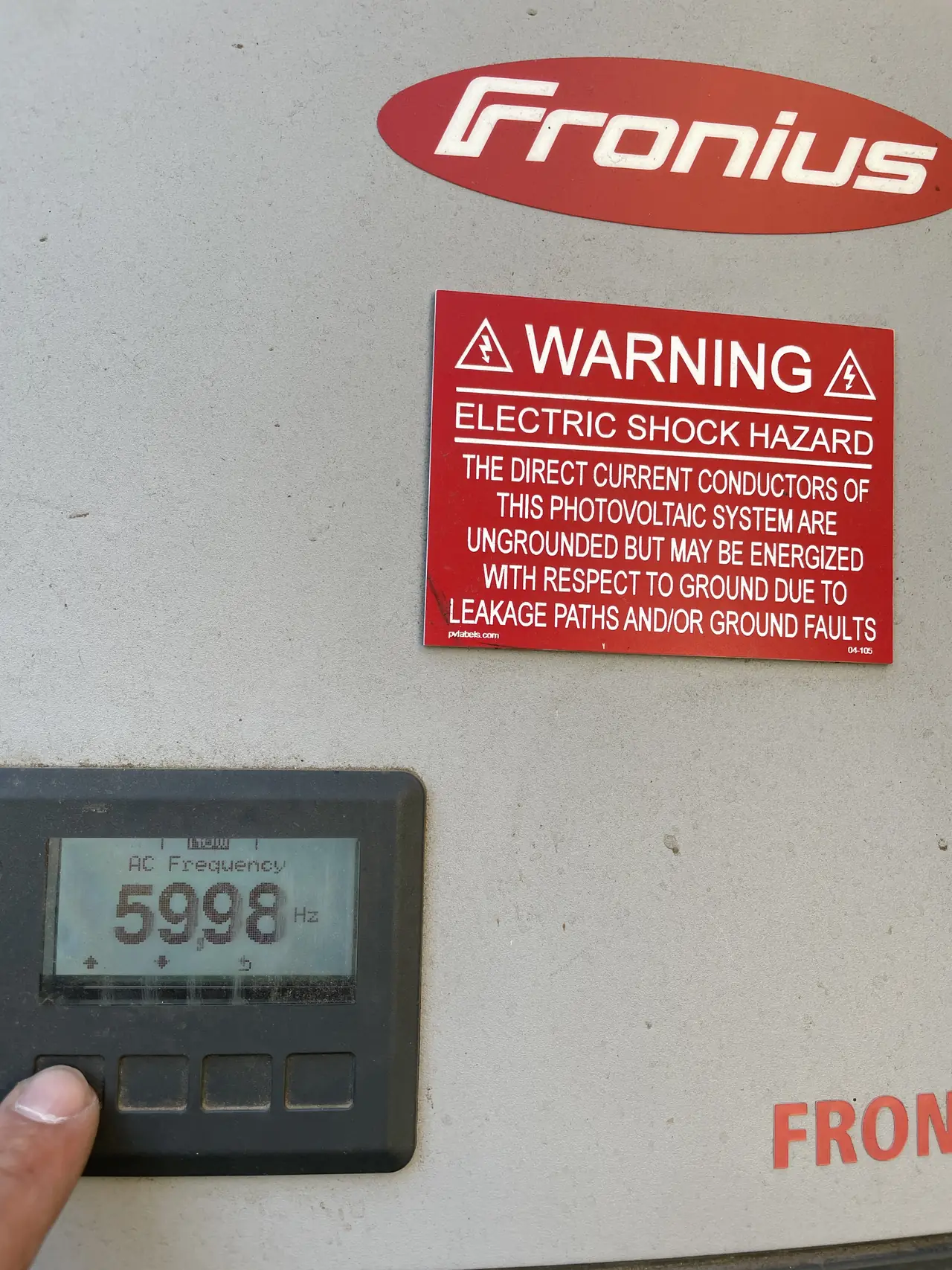 Fronius inverter mounted on an exterior wall with its display lit, Sylmar