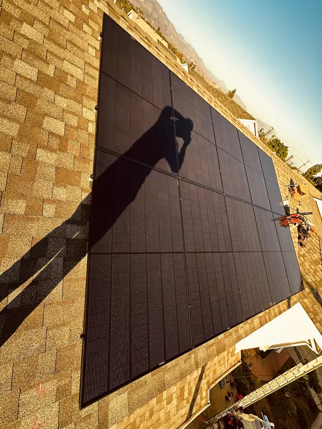 Black solar modules on a composition shingle roof with hills behind, Sylmar