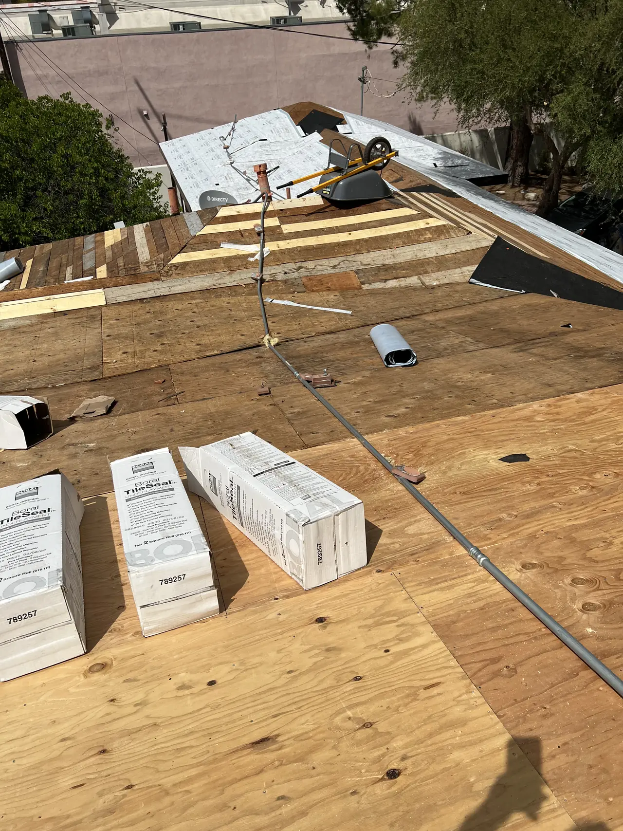 New plywood sheathing on a low-slope roof with roofing materials stacked on it, Tarzana