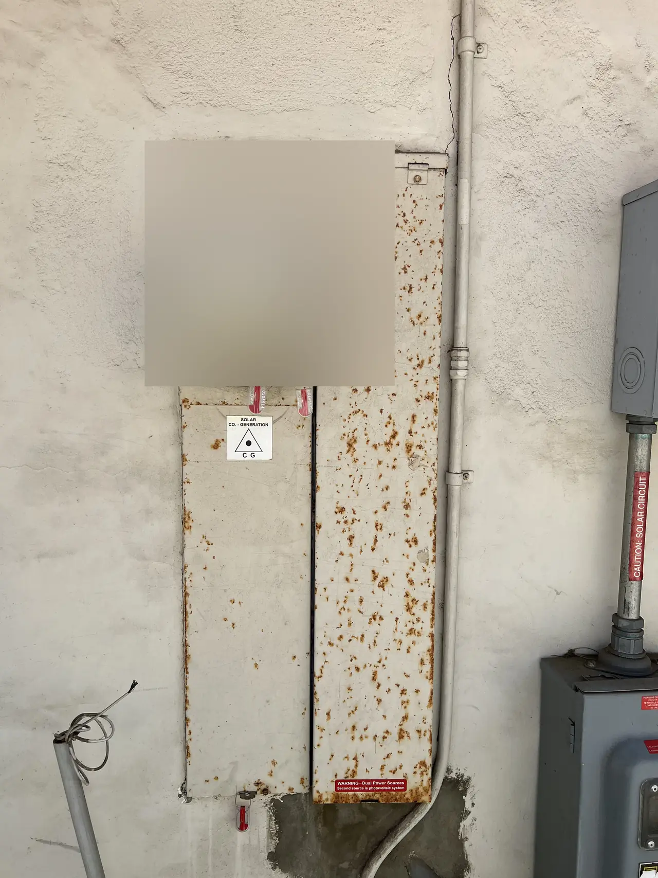 Rusted older meter panel on a stucco wall before replacement, with the meter face obscured, Tarzana