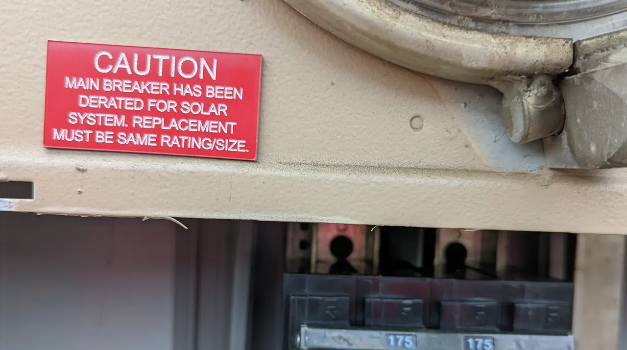 Caution label stating the main breaker has been derated for the solar system, with the 175-amp main breaker below it, Tarzana