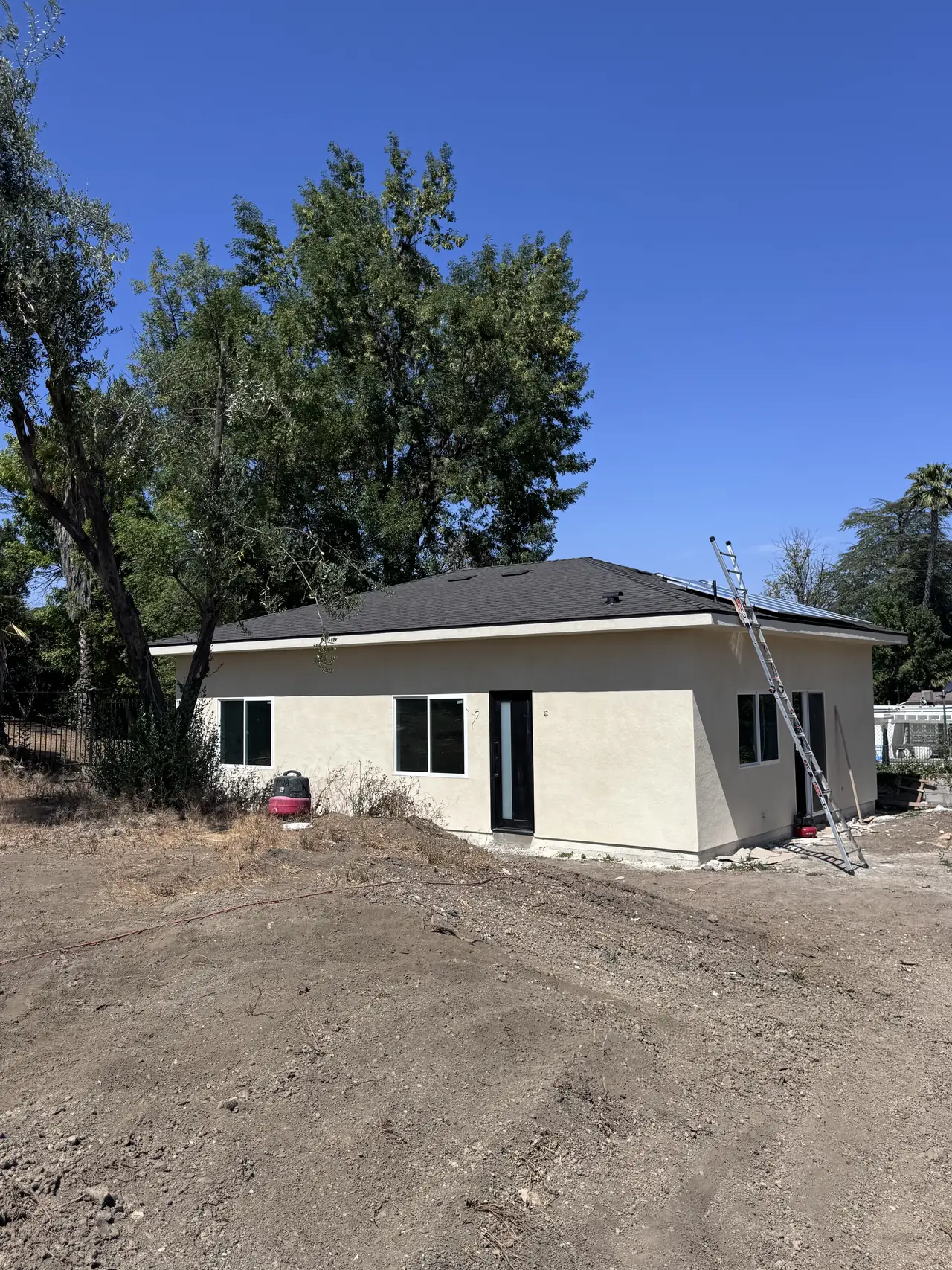 Newly built single-story detached ADU with stucco walls and a composition shingle roof, before solar, on a graded lot, Tarzana
