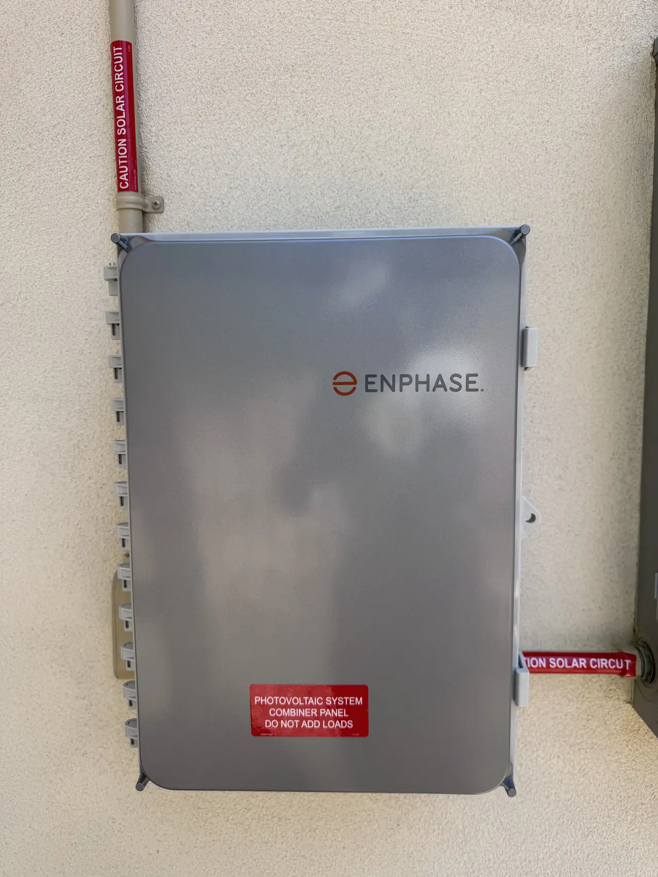 Enphase IQ Combiner on the ADU's stucco wall with red solar circuit labels on the conduit, Tarzana