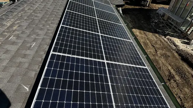 Six solar modules in two columns on the composition shingle roof of a new two-story house, with the neighboring build site at the edge of the frame, Tarzana