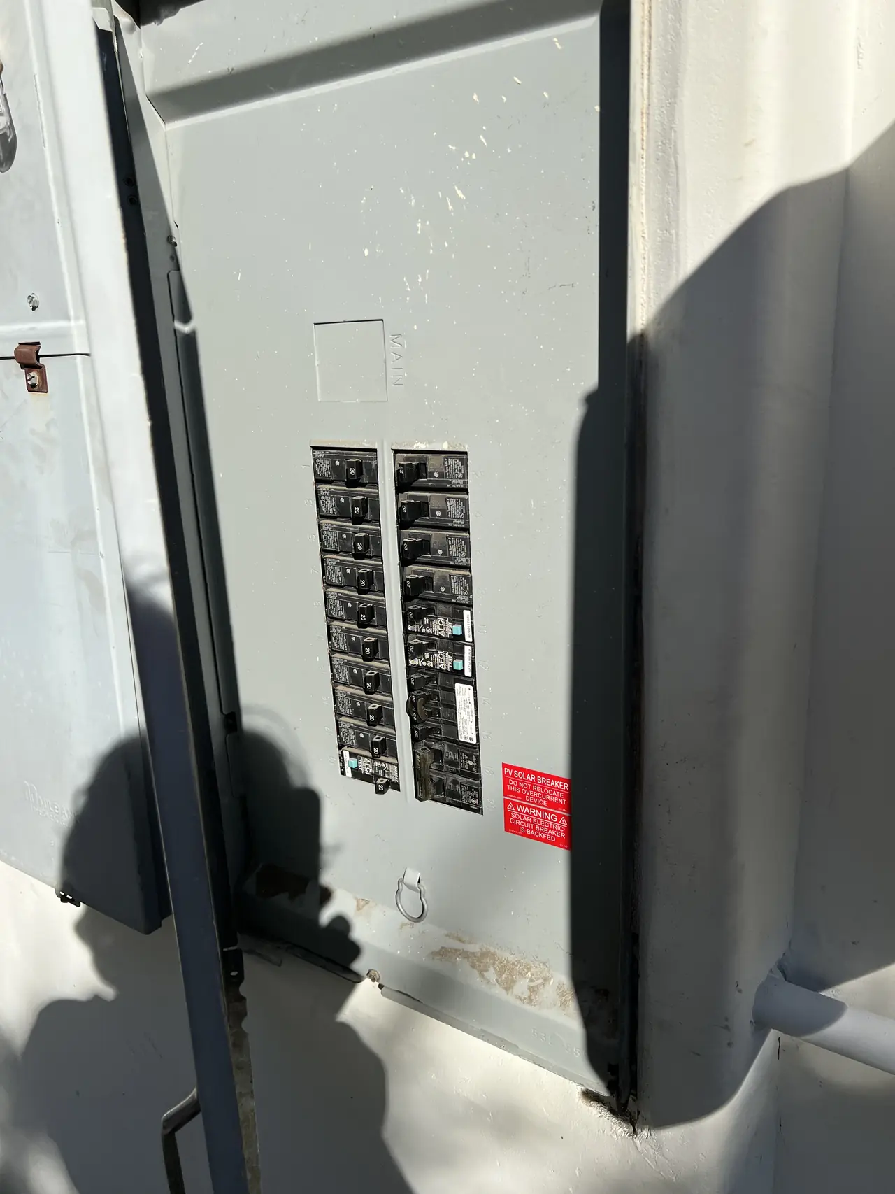Service panel with the door open showing the dead front and a solar backfeed warning label, Tarzana