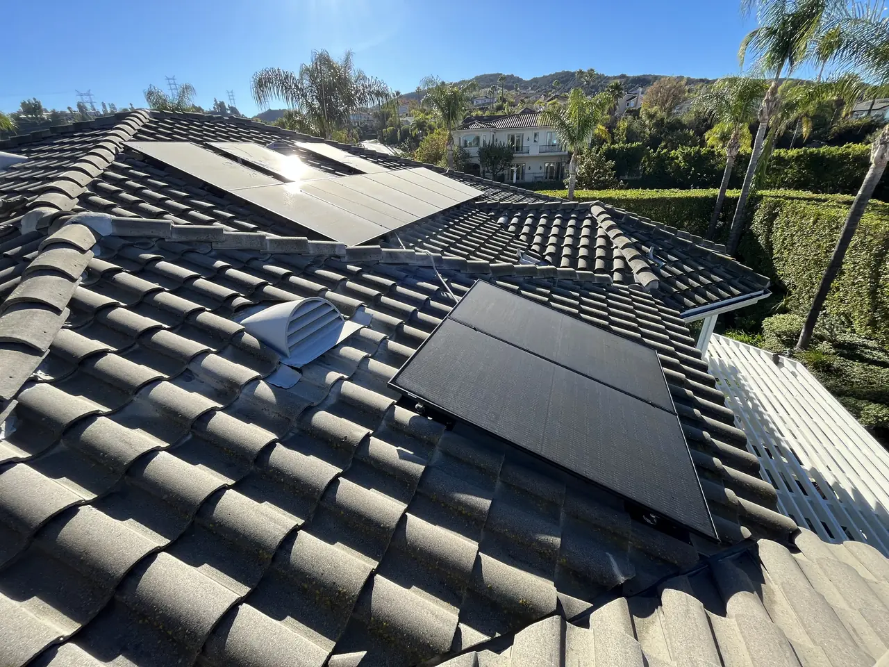 Small groups of black solar modules on several planes of an S-tile roof, Tarzana
