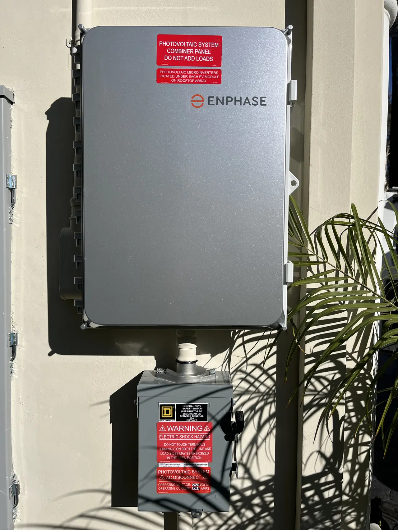 Enphase combiner and a fused disconnect mounted on a stucco wall with warning labels, Tarzana