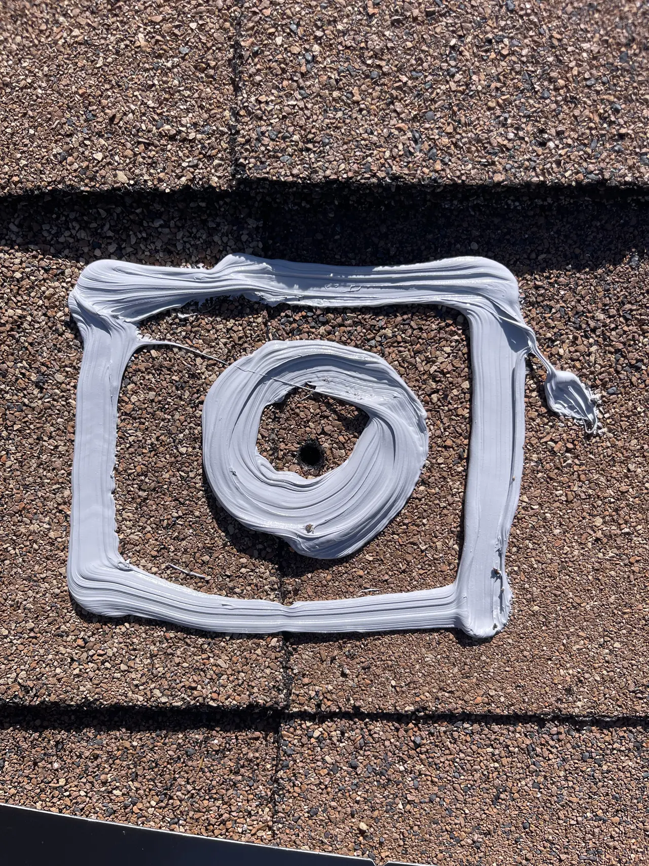 Rings of sealant around a drilled mount hole on a brown shingle roof, Tujunga
