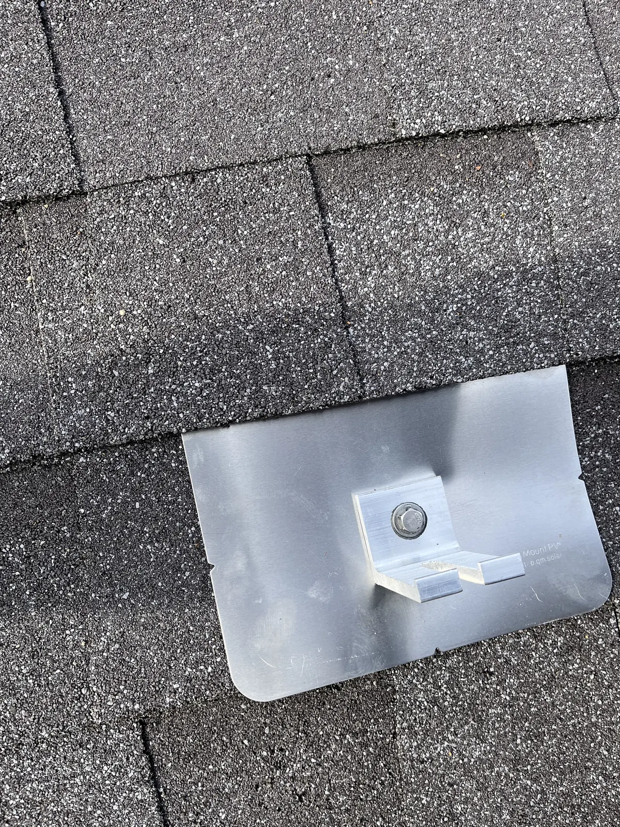 An aluminum L-foot on a flashing plate slid under a dark shingle course, Tujunga