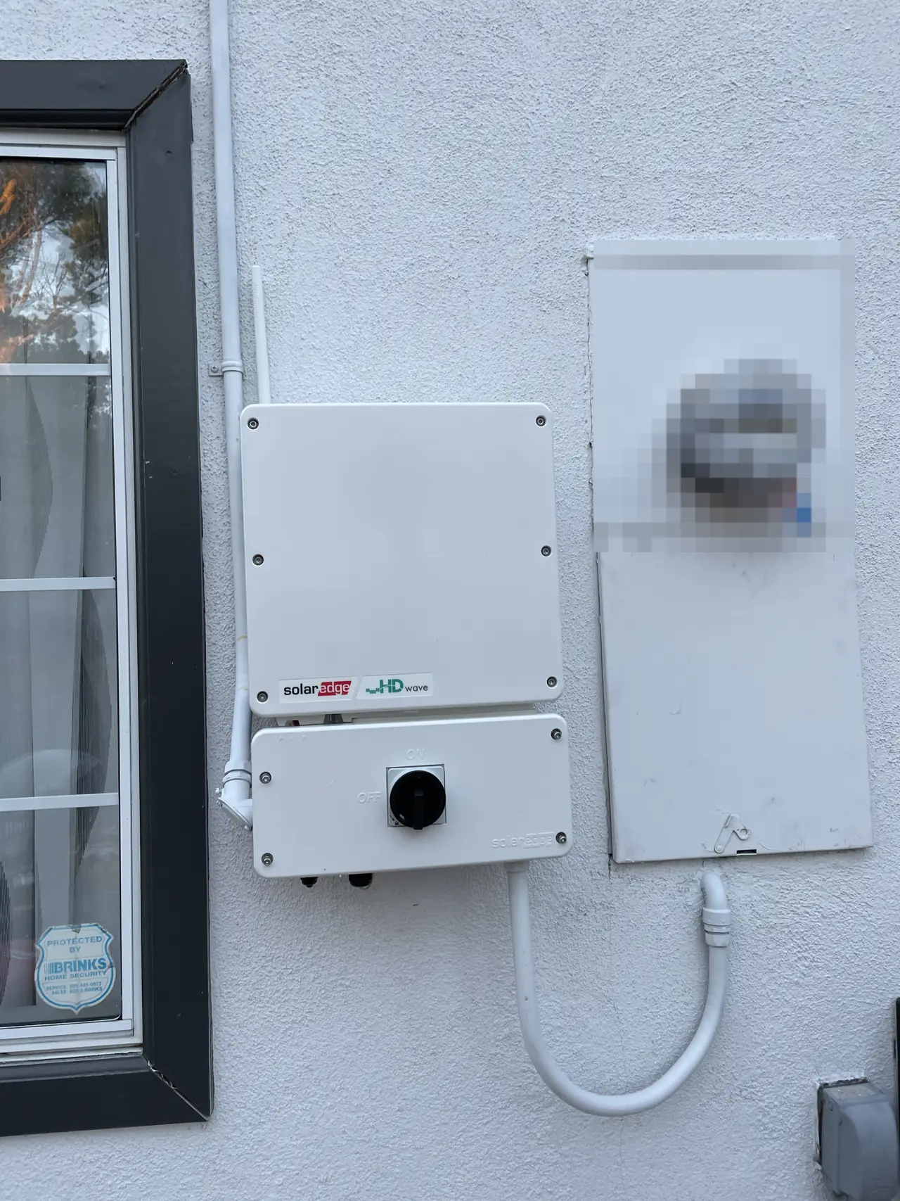 A SolarEdge HD-Wave inverter on a white stucco wall next to the electrical service, Tujunga