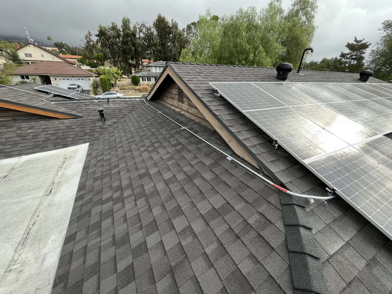 Solar modules beside a roof gable on dark shingles, Tujunga
