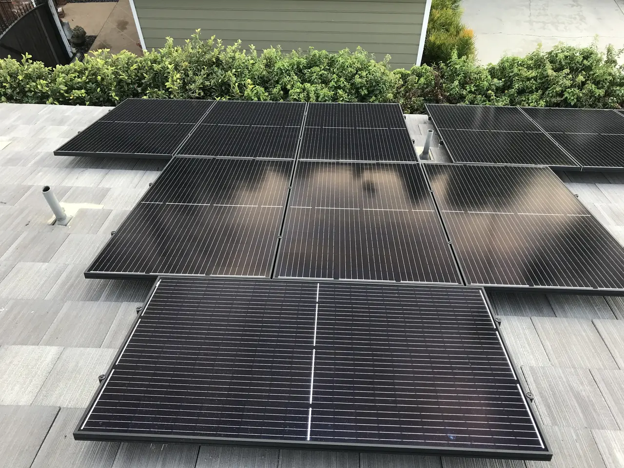 A run of black modules along the ridge of a tile roof with trees and rooftops behind, Van Nuys, Los Angeles