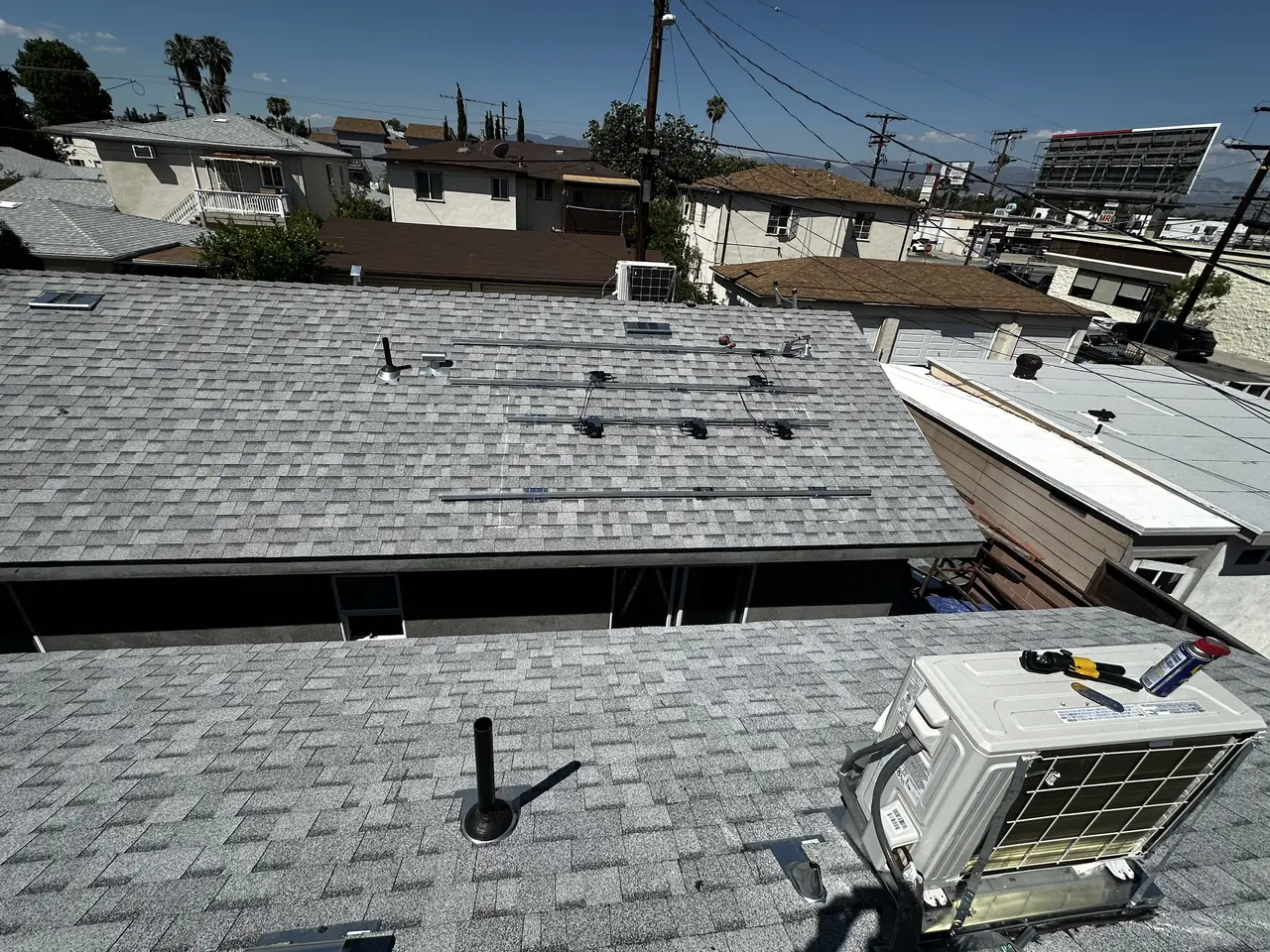 Looking along a narrow lot over the roofs of two new buildings toward neighboring rooftops, Van Nuys, Los Angeles