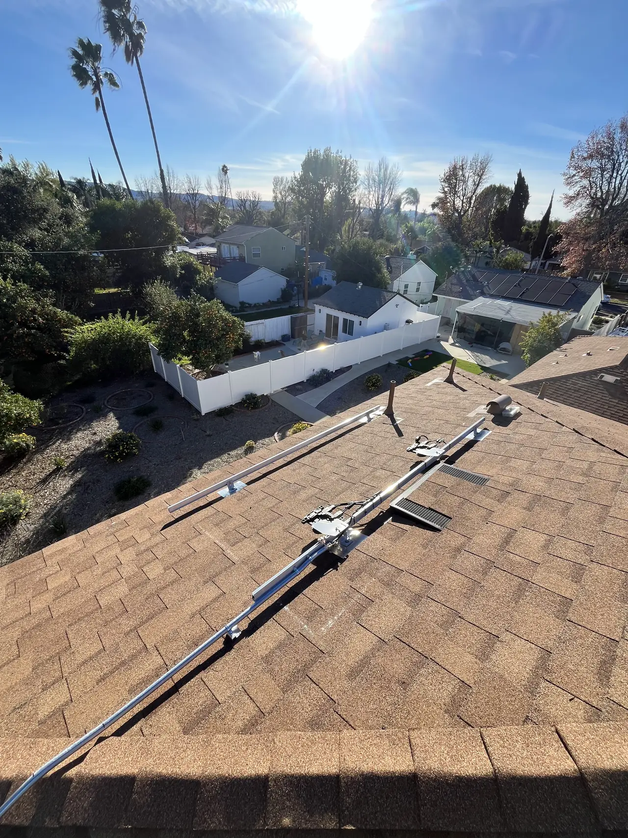 Mounting rails running across a shingle roof with conduit and a junction box in place before modules are installed, Van Nuys, Los Angeles
