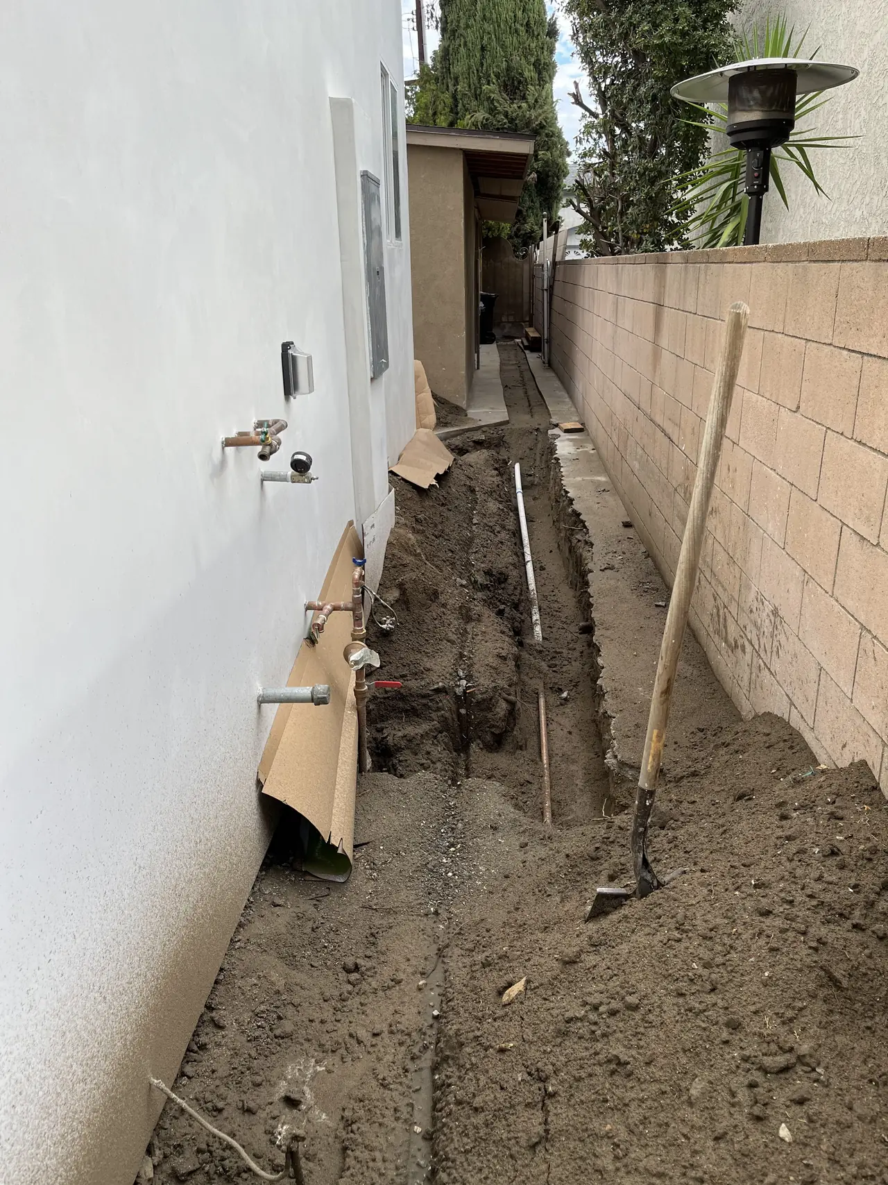 A narrow open trench running along the side of a house toward the rear of the lot, Van Nuys, Los Angeles