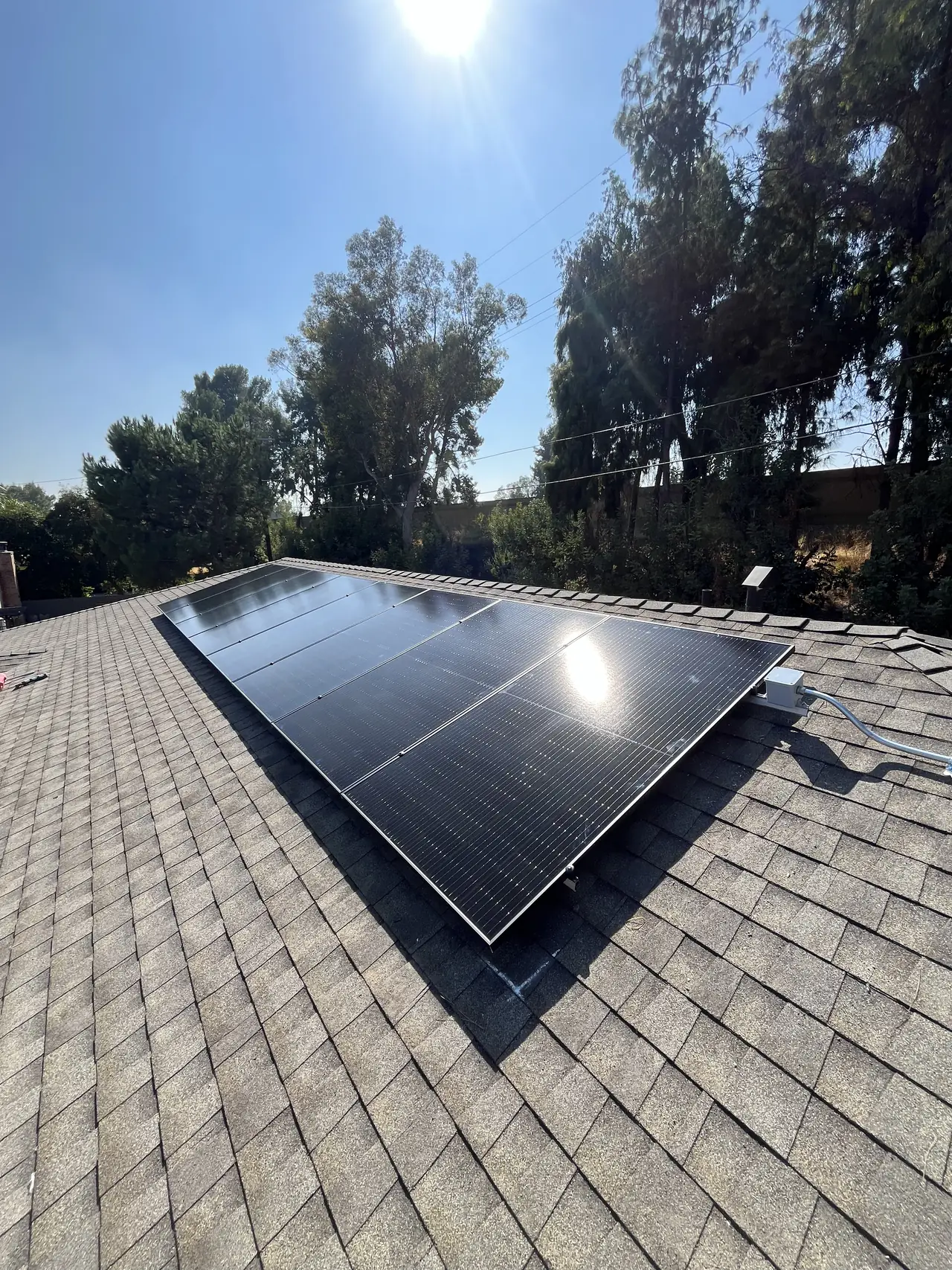 Black modules installed on the sunward plane of a gray shingle hip roof, Van Nuys, Los Angeles