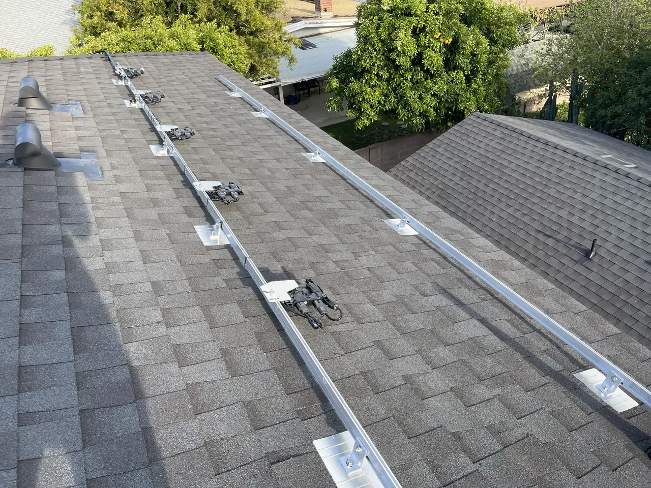 Mounting rails set across a dark gray shingle roof with the neighborhood visible beyond, Van Nuys, Los Angeles