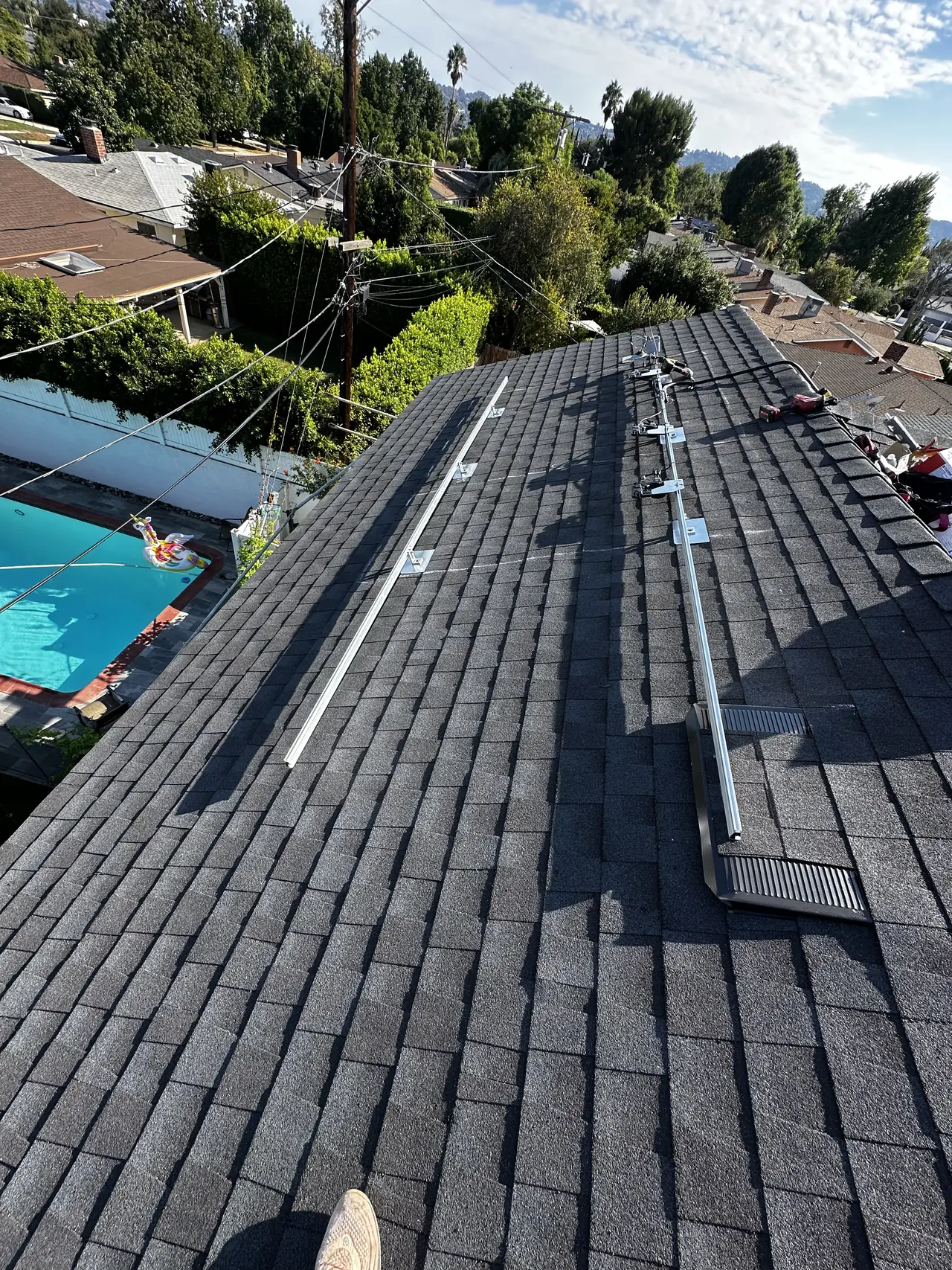 A dark charcoal shingle roof seen across its slope with a pool and hedge below, Van Nuys, Los Angeles