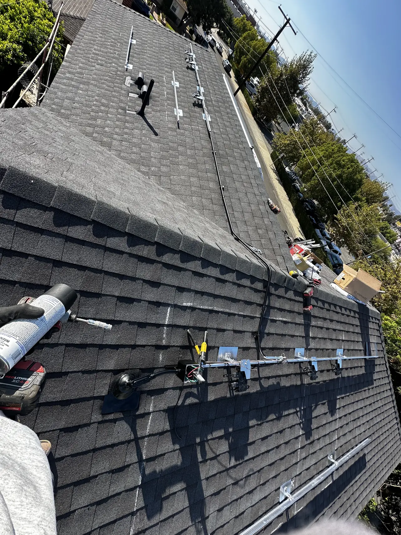 Wide view along a dark shingle roof toward trees and neighboring rooftops, Van Nuys, Los Angeles