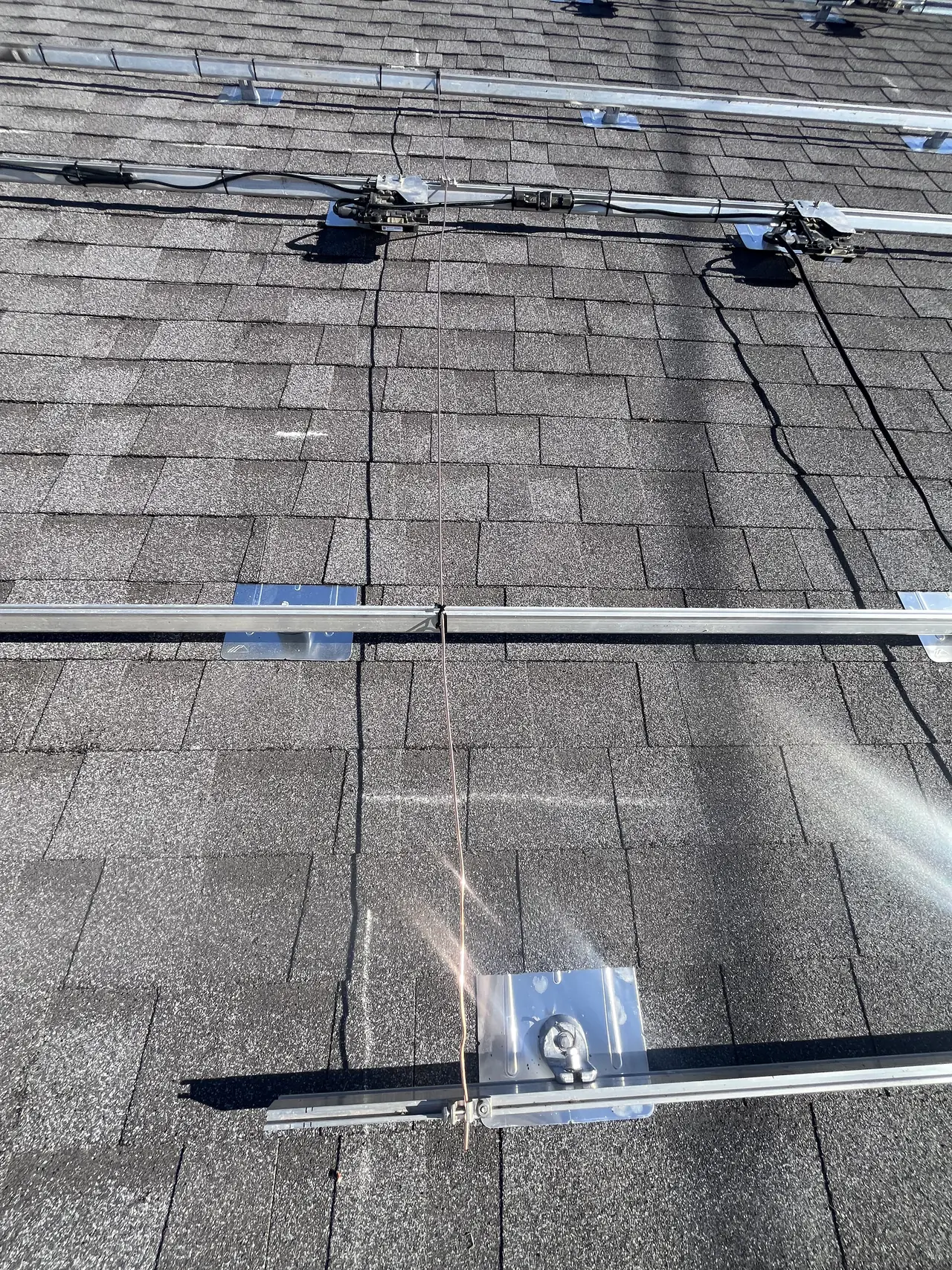 Enphase microinverter mounted under the rail on a shingle roof, West Hills