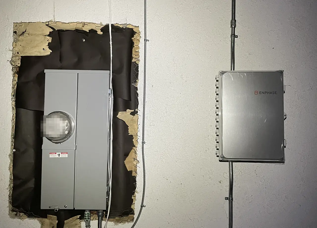A new main service panel set into an opened section of stucco wall with a combiner enclosure mounted beside it, Woodland Hills