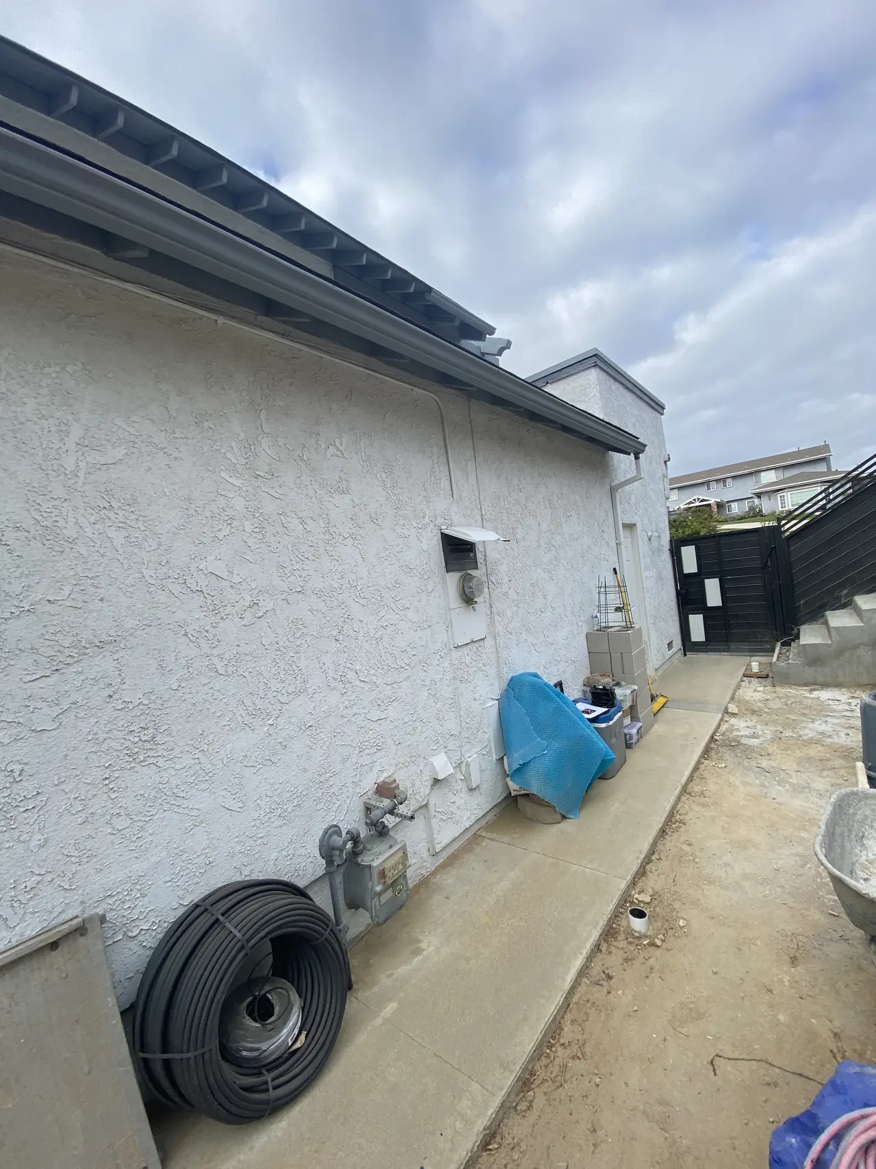 A yellow tape measure stretched along a stucco wall from a gas riser to the electrical equipment location, Woodland Hills