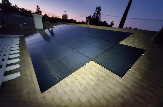 A large black solar array spread across a wide composition shingle roof at dusk, Woodland Hills